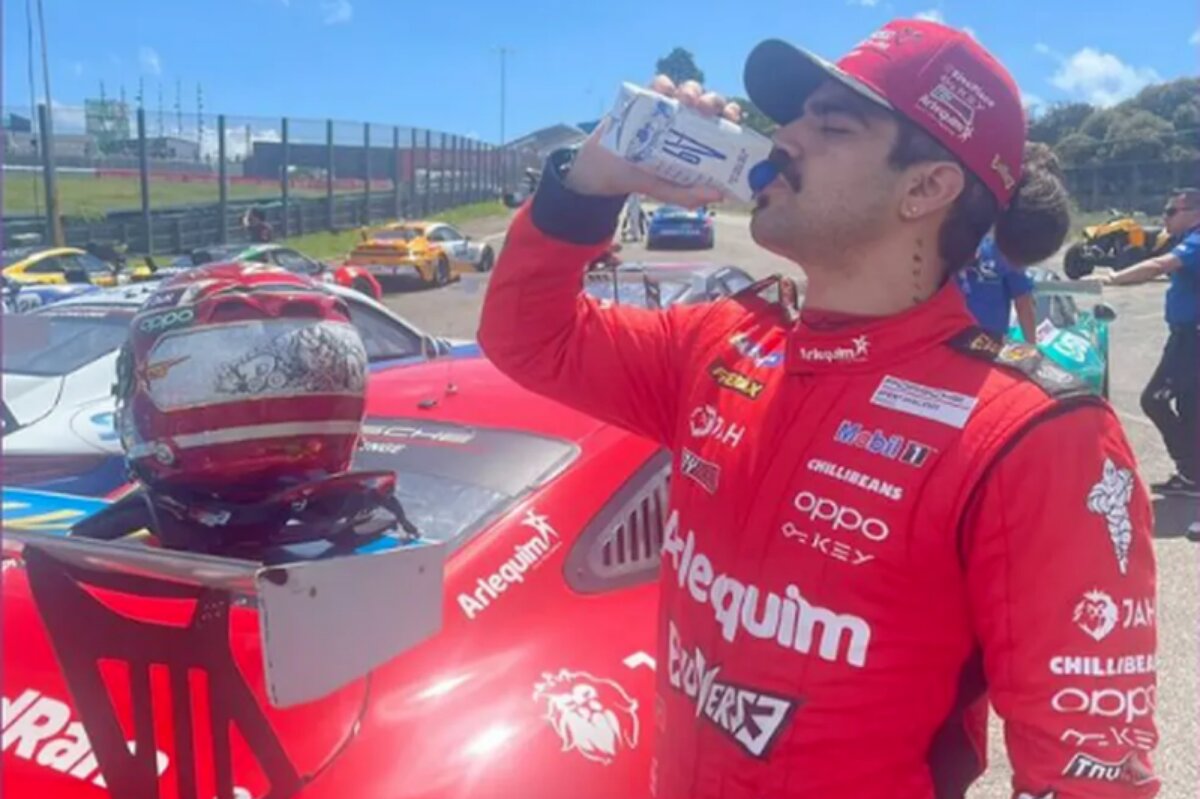 Caio Castro de uniforme de automobilismo, vermelho, bebendo água