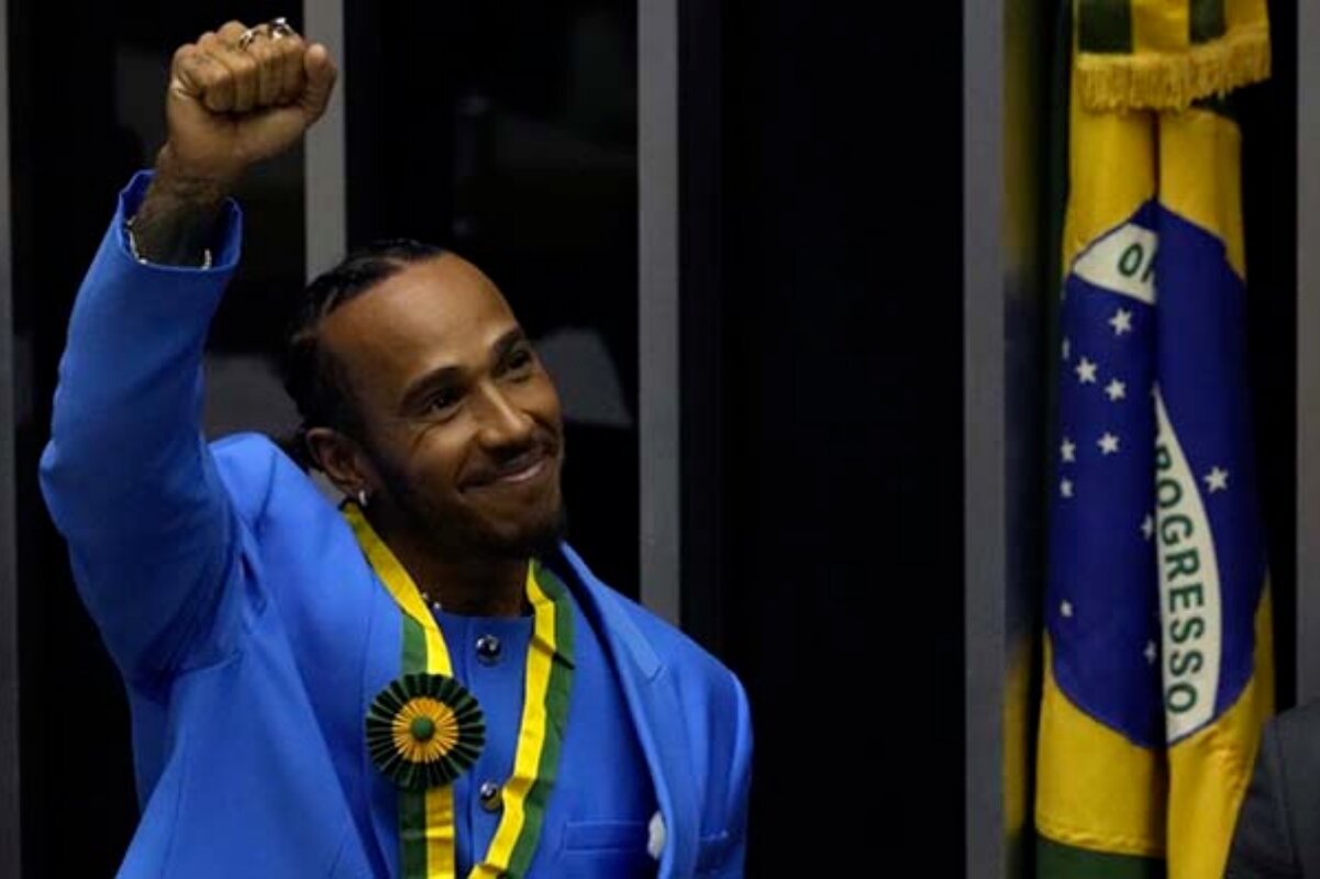 Lewis Hamilton com o punho cerrado, de terno azul e medalha de cidadão brasileiro