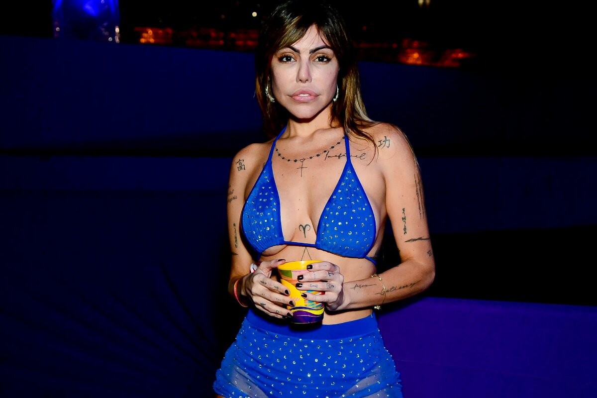Liziane Gutierrez de azul, segurando um copo
