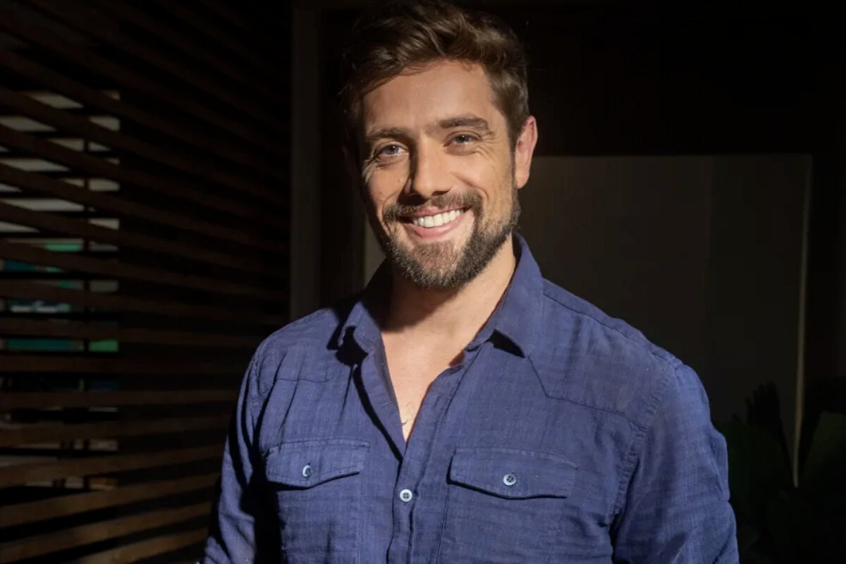 Rafael Cardoso de camisa azul de botões, sorrindo
