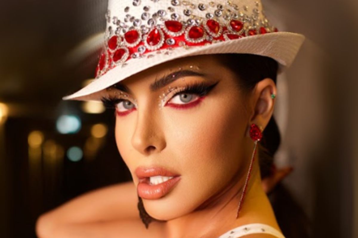 Carla Prata, maquiada, de chapéu, em lançamento de CD do Carnaval 2023