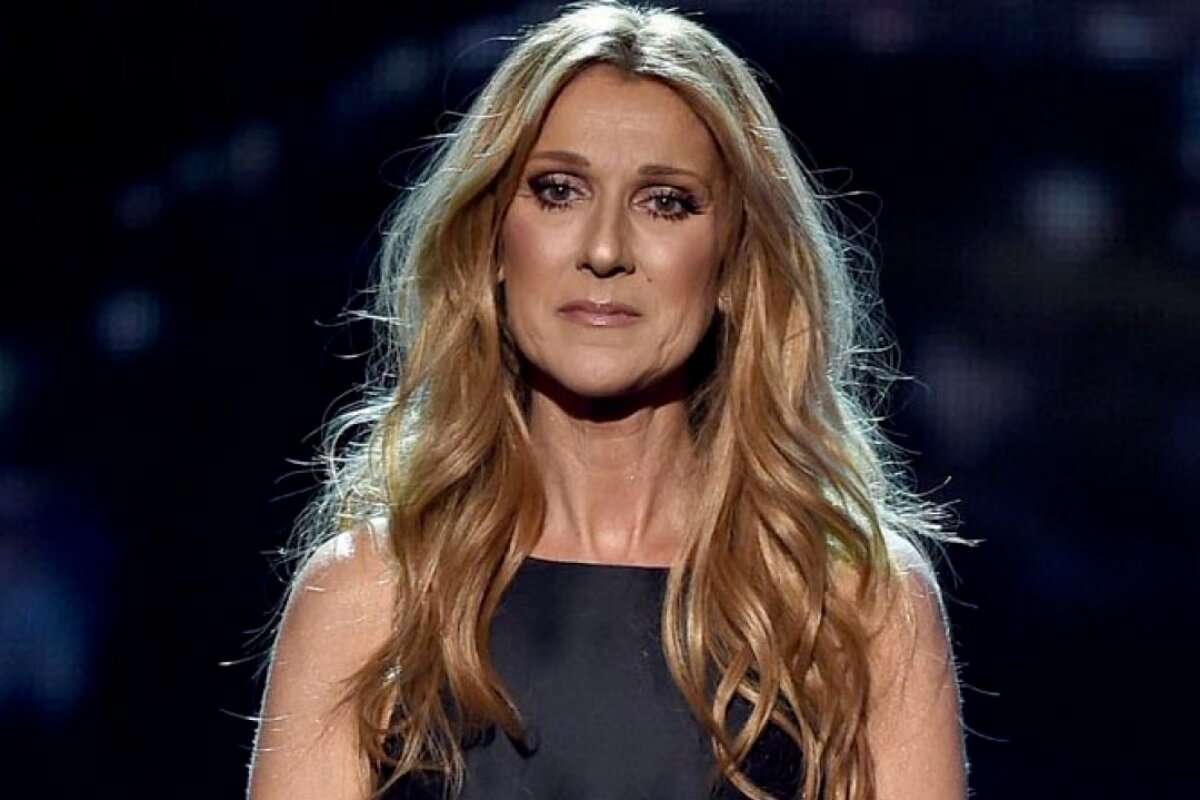Céline Dion com expressão triste, de cabelos soltos