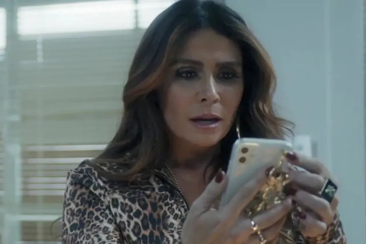 Helô (Giovanna Antonelli) espantada diante de mensagem no celular, cena de 'Travessia'