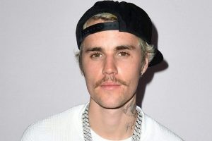 Justin Bieber de boné preto virado pra trás e camisa branca