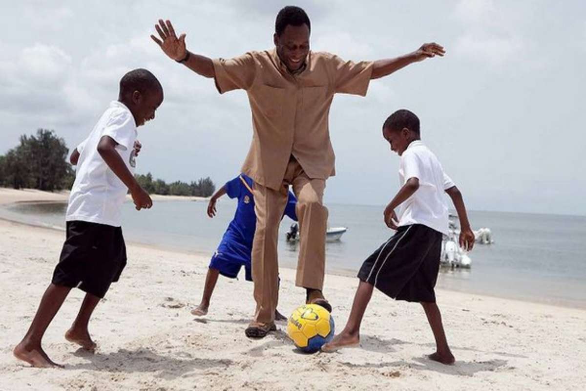 Pelé jogando futebol na praia com crianças