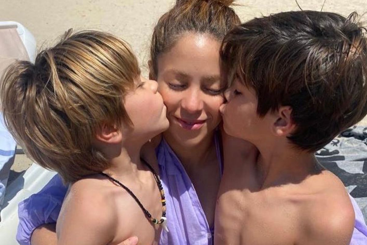 shakira recebendo beijos na bochecha dos dois filhos na praia