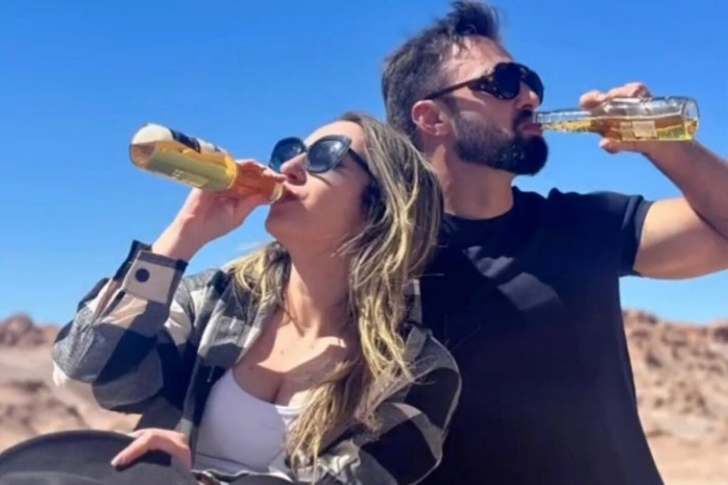 Amanda e Felipe Weiber bebendo cerveja, ambos de óculos escuros  