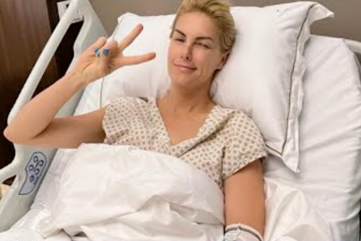 Ana Hickmann fazendo sinal de positivo, deitada na cama do hospital
