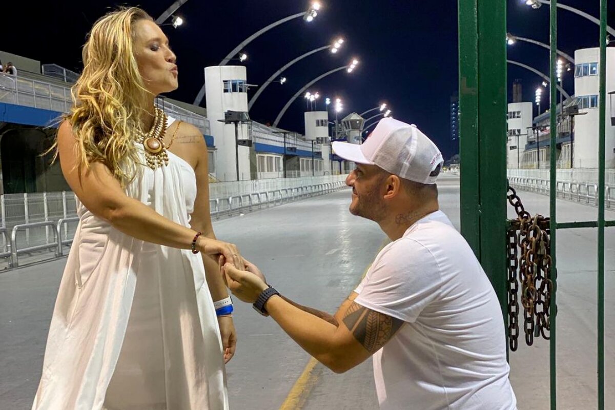 Ana Thais Matos em pé e o namorado, de joelhos, segurando a mão dela, pedindo em casamento