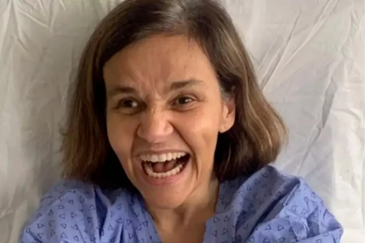 Claudia Rodrigues sorrindo, na cama do hospital