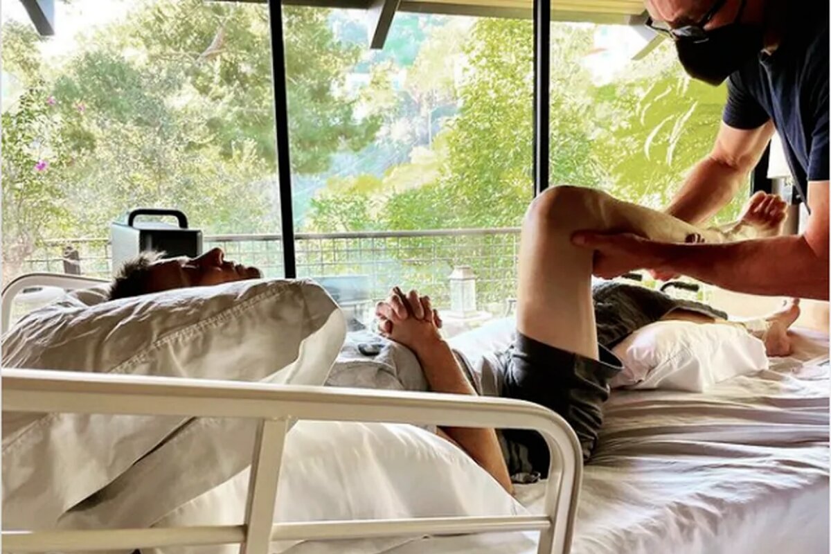 Jeremy Renner deitado, fazendo fisioterapia