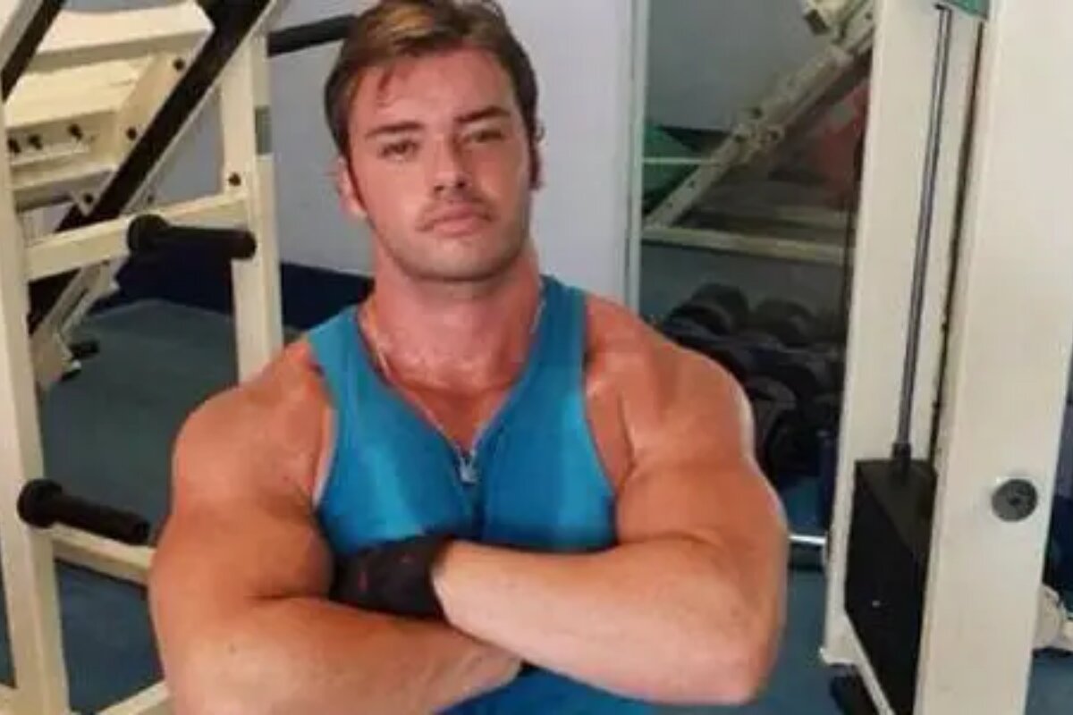 Thor Batista na academia, de braços cruzados, camiseta regata azul