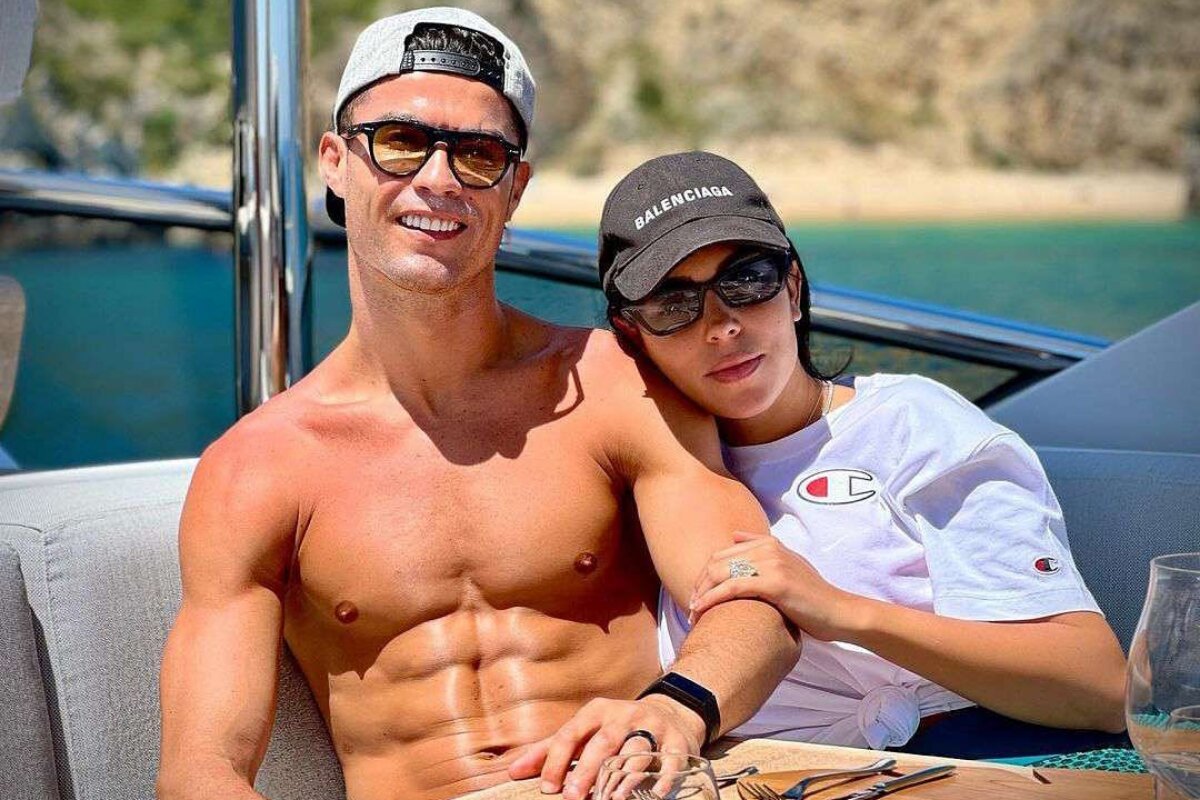 Cristiano Ronaldo sem camisa, sentado ao lado da mulher, Georgina Rodriguez, em um barco