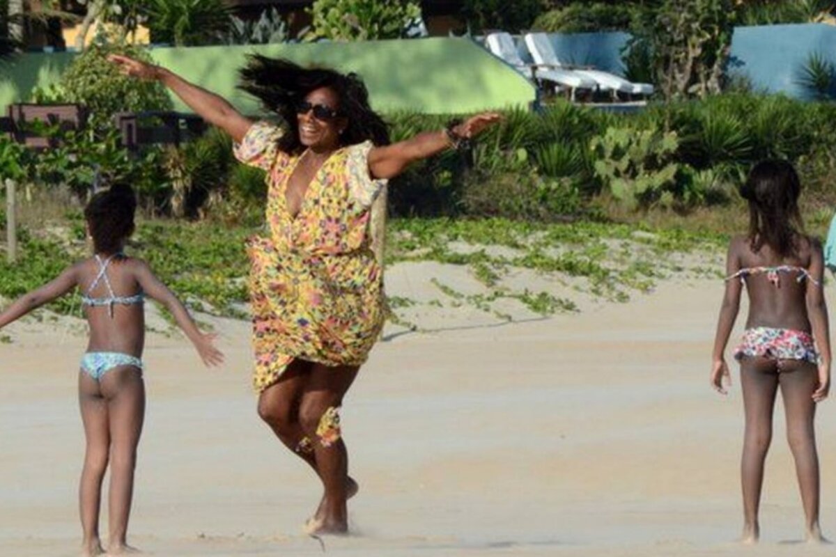 Gloria Maria em Búzios, na areia da praia com as filhas