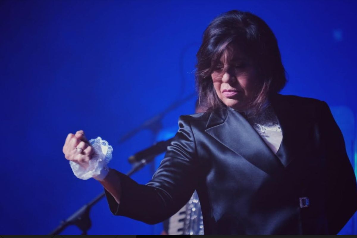 Roberta Miranda com a mão fechada mostrando sua força, em cenário azul