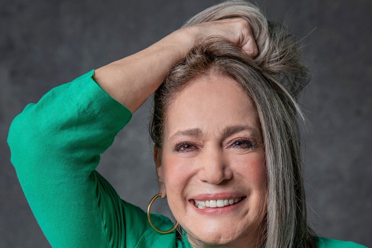 Susana Veiira de camisa verde, com a mão pra cima, no cabelo