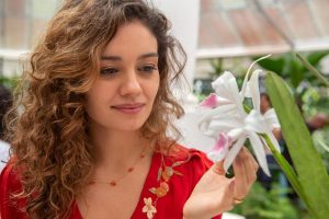 Maíra (Sophie Charlotte) observando uam flor em cena de 