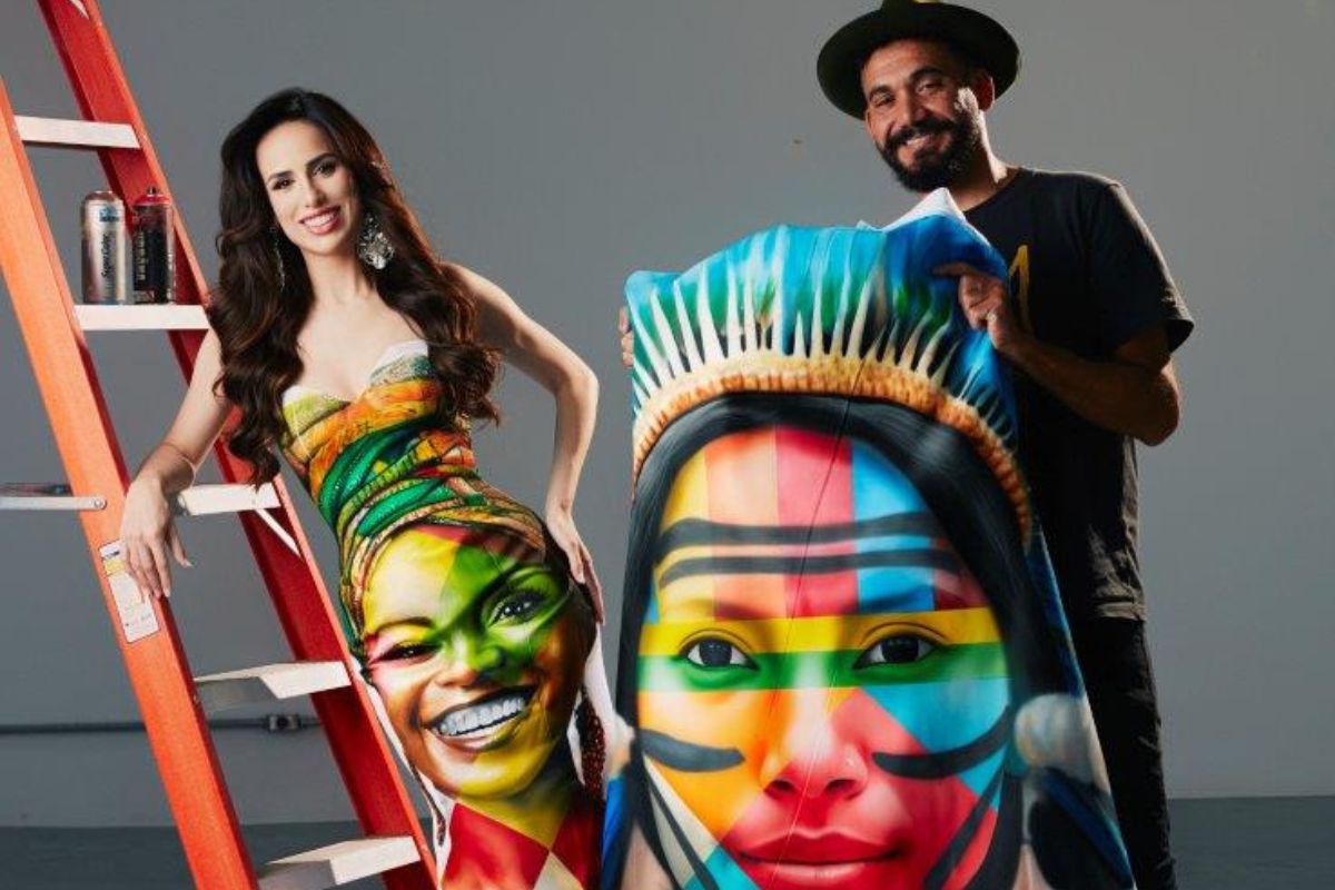 Mia Mamede posa em uma escada com vestido pintado pelo muralista Eduardo Kobra
