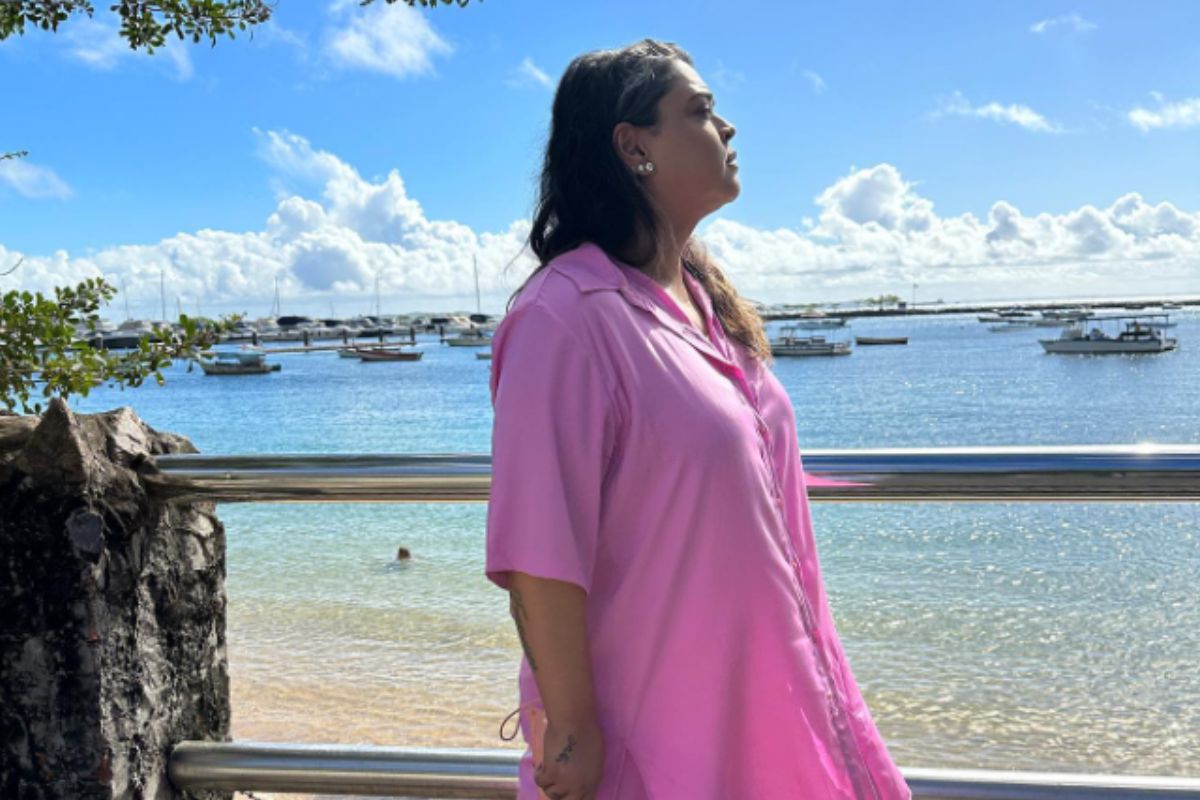 Preta Gil, com roupa cor de rosa, olhando o mar