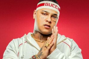 MC Ryan com faixa no cabelo esfregando as mãos