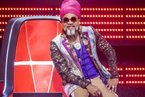 Carlinhos Brown sentado na cadeira do The Voice Brasil