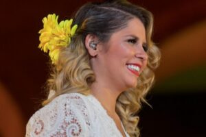 Marília Mendonça com flor amarela no cabelo, sorrindo
