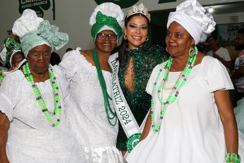 Gyselle Soares de coroa e vestido verde de brilhos ladeada por baianas 