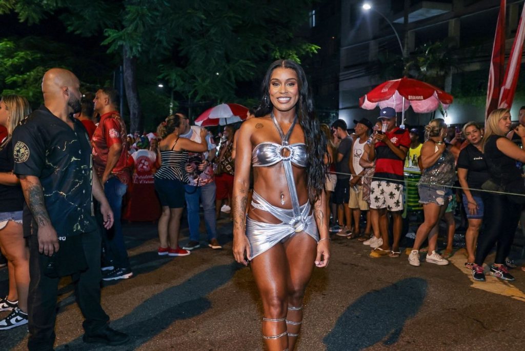 MC Rebecca de saia e top prata de recortes , com sandália gladiadora prata 