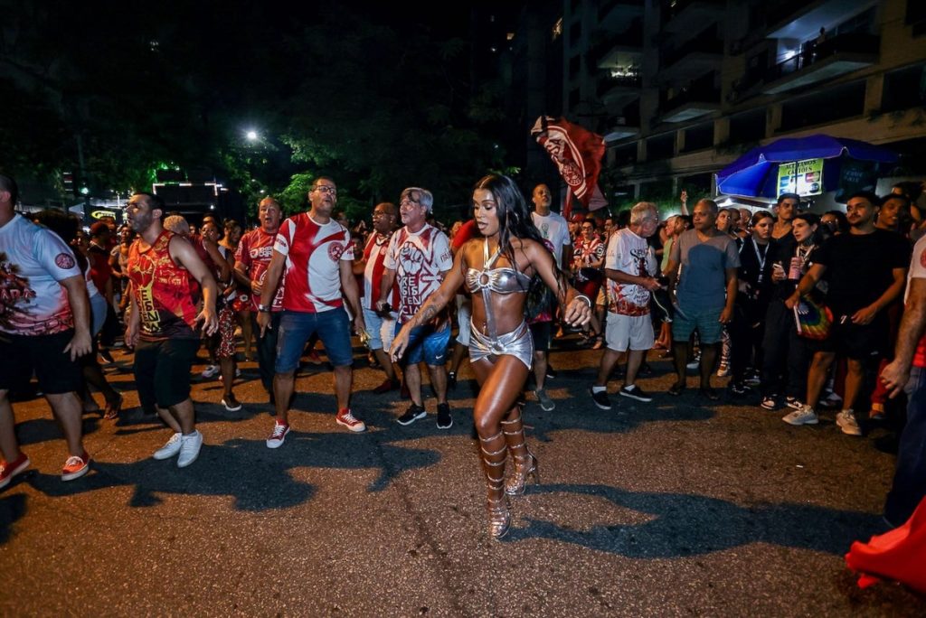 MC Rebecca de saia e top prata de recortes , com sandália gladiadora prata 