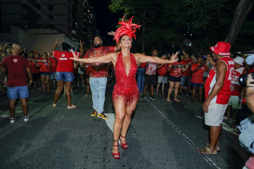 Viviane Araújo de adereço de penas na cabeça, body estilizado vermelho