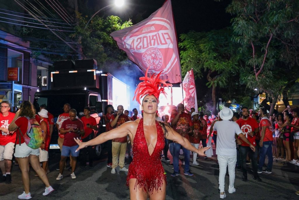 Viviane Araújo de adereço de penas na cabeça, body estilizado vermelho