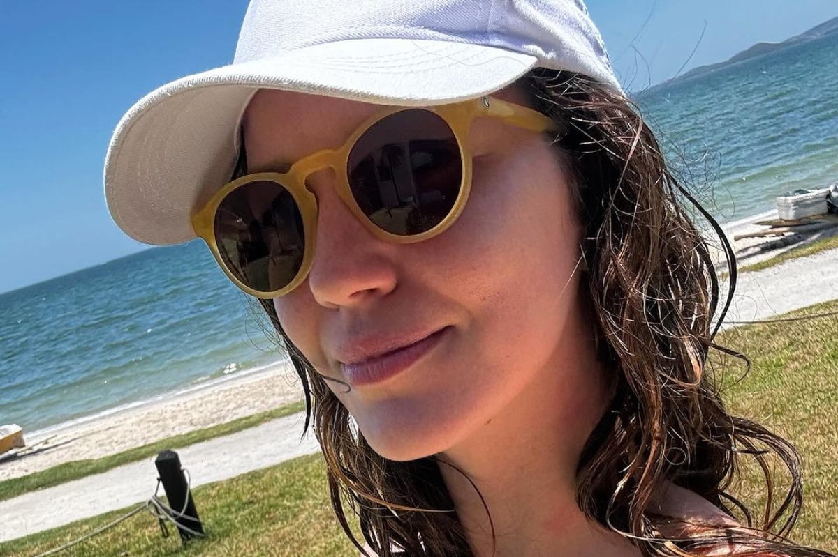 Nathalia Dill de boné branco e óculos escuros, na praia