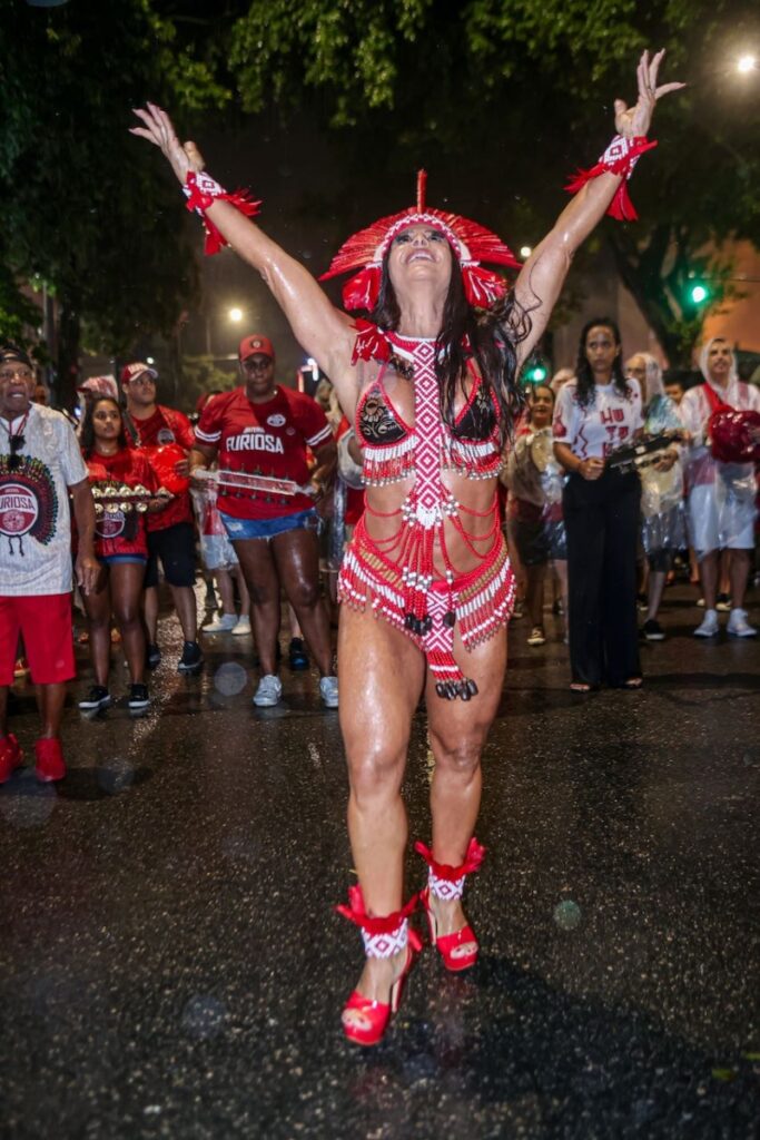 Viviane Araújo fantasiada de indígena, com cocar e biquíni vermelho e branco, sandálias vermelhas 
