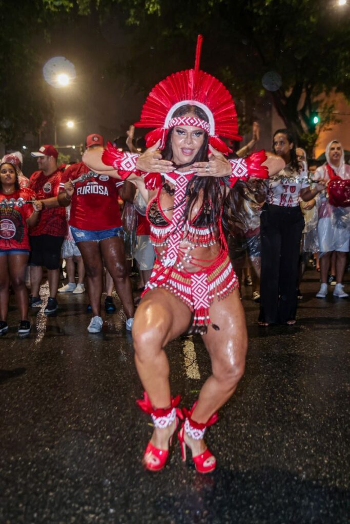 Viviane Araújo fantasiada de indígena, com cocar e biquíni vermelho e branco, sandálias vermelhas 