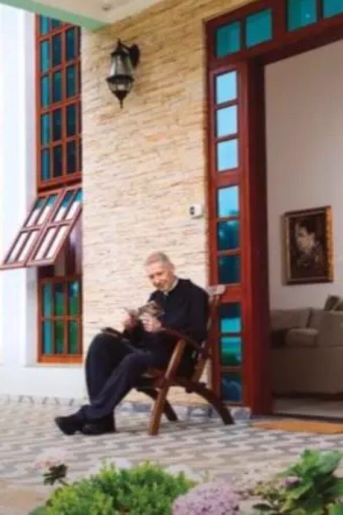 Padre Marcelo Rossi sentado numa cadeira, na fachada de casa 