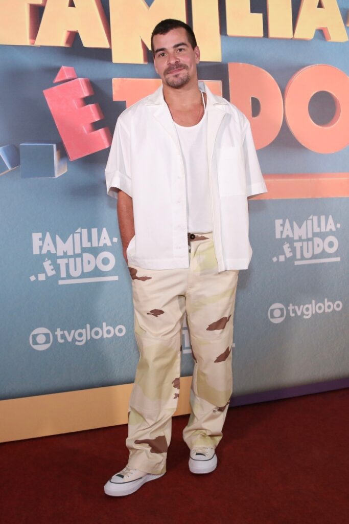 Thiago Martins de camisa e camiseta branca, calça bege e marrom, na festa da novela Família é Tudo 