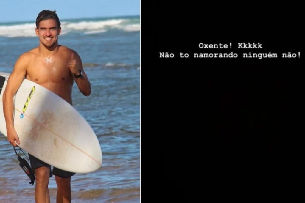 João Lamenha Barreto segurando prancha de surf, fazendo sinal de positivo, na praia
