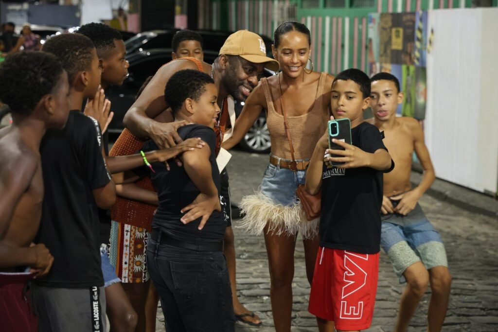 Taís Araújo e Lázaro Ramos cercados por crianças da Mangueira 