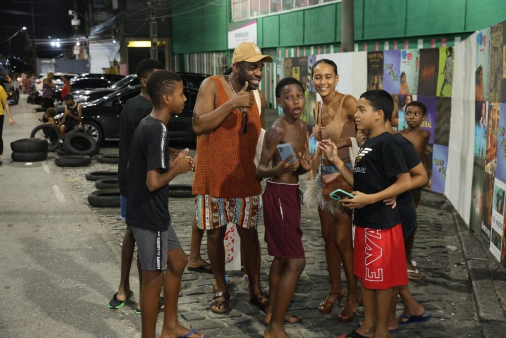 Taís Araújo e Lázaro Ramos cercados por crianças da Mangueira 