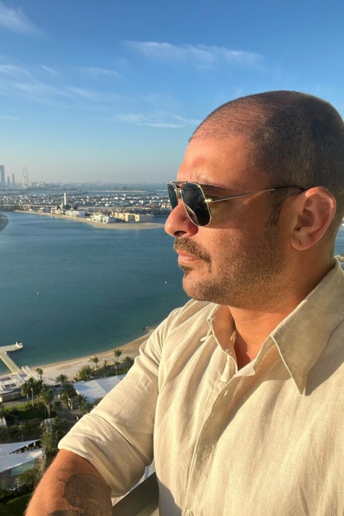 Diogo Nogueira de óculos escuros, camisa branca, admirando o mar 