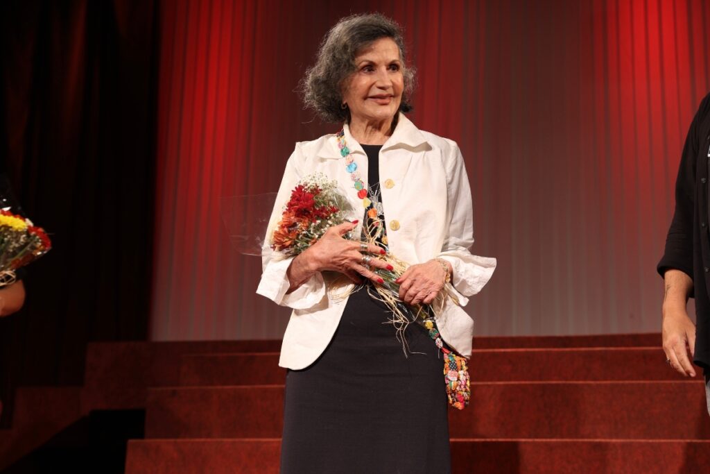 Rosamaria Murtinho segurando buquê de flores, no palco