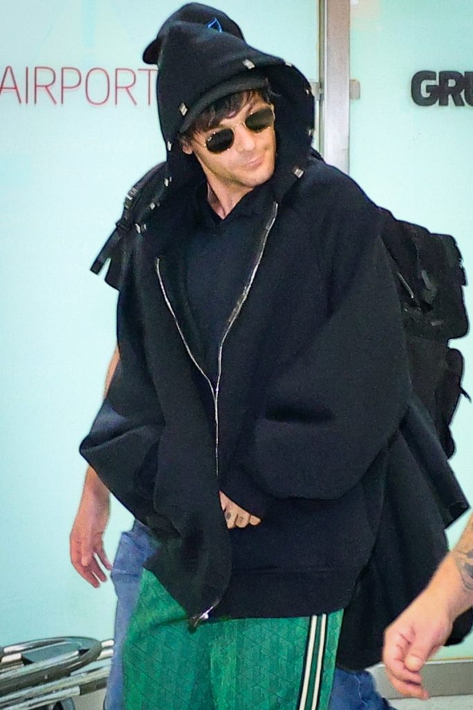Louis Tomlinson de casaco preto de capuz e óculos escuros 