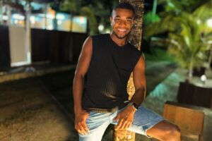 Davi Brito de bermuda jeans e camisa regata preta, sorrindo