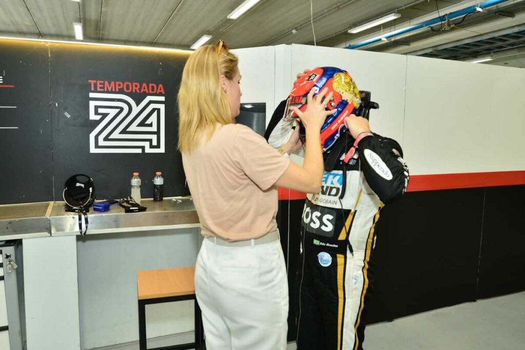 Ana Hickmann colocando capacete em Edu Guedes dentro de carro na Porsche Cup Brasil