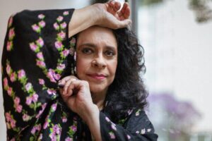 Gal Costa de camisa preta com estampa de flores cor de rosa