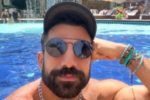 Kaysar Dadour na piscina de boné e óculos escuros