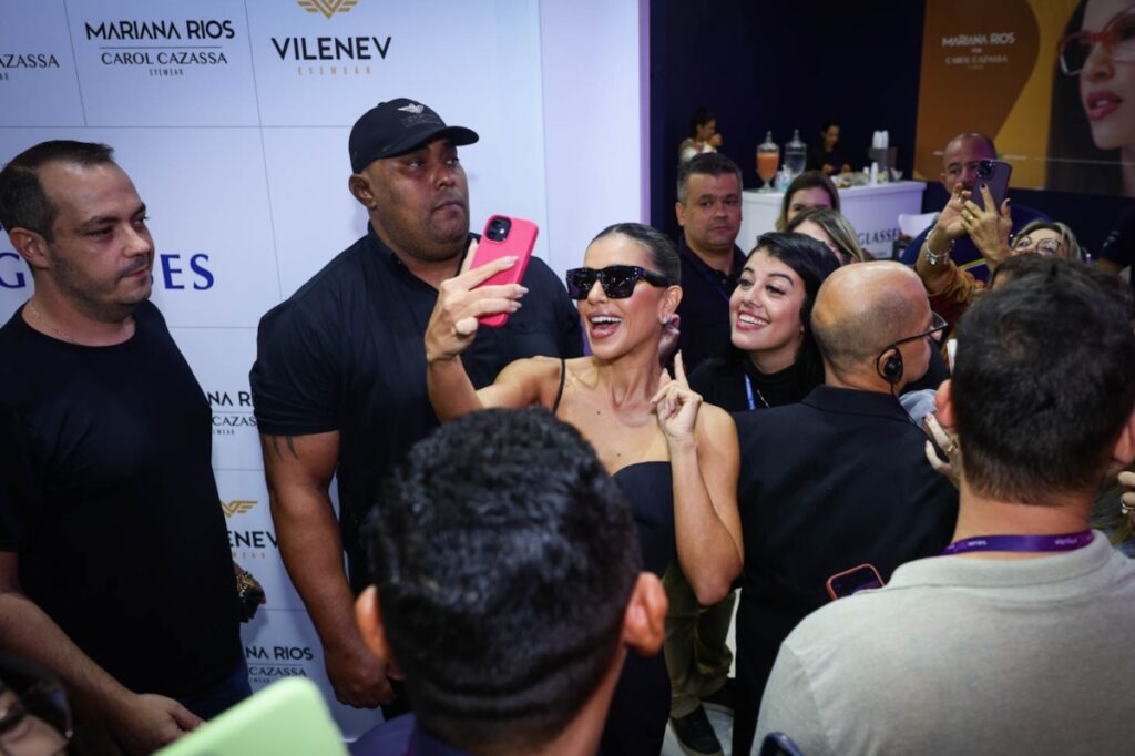 Mariana Rios de vestido preto e óculos escuros preto, fazendo selfie com fãs 