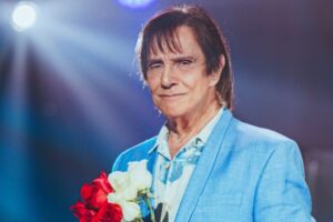 Roberto Carlos de terno azul segurando rosa vermelha