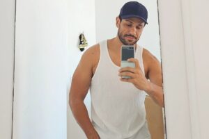 Amaury Lorenzo de boné preto e regata branca, fazendo selfie