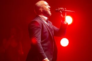 belo cantado em show com luz vermelha e terno azul